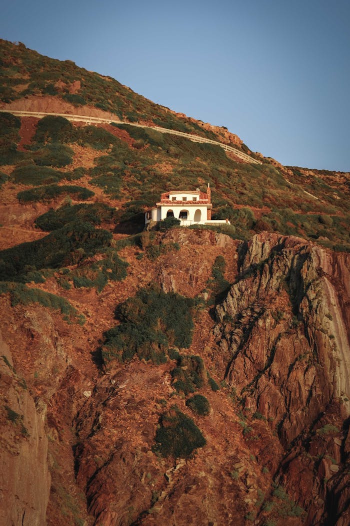 Breathtaking scenery of lonely residential villa located on edge of massive rocky cliff under cloudless blue sky